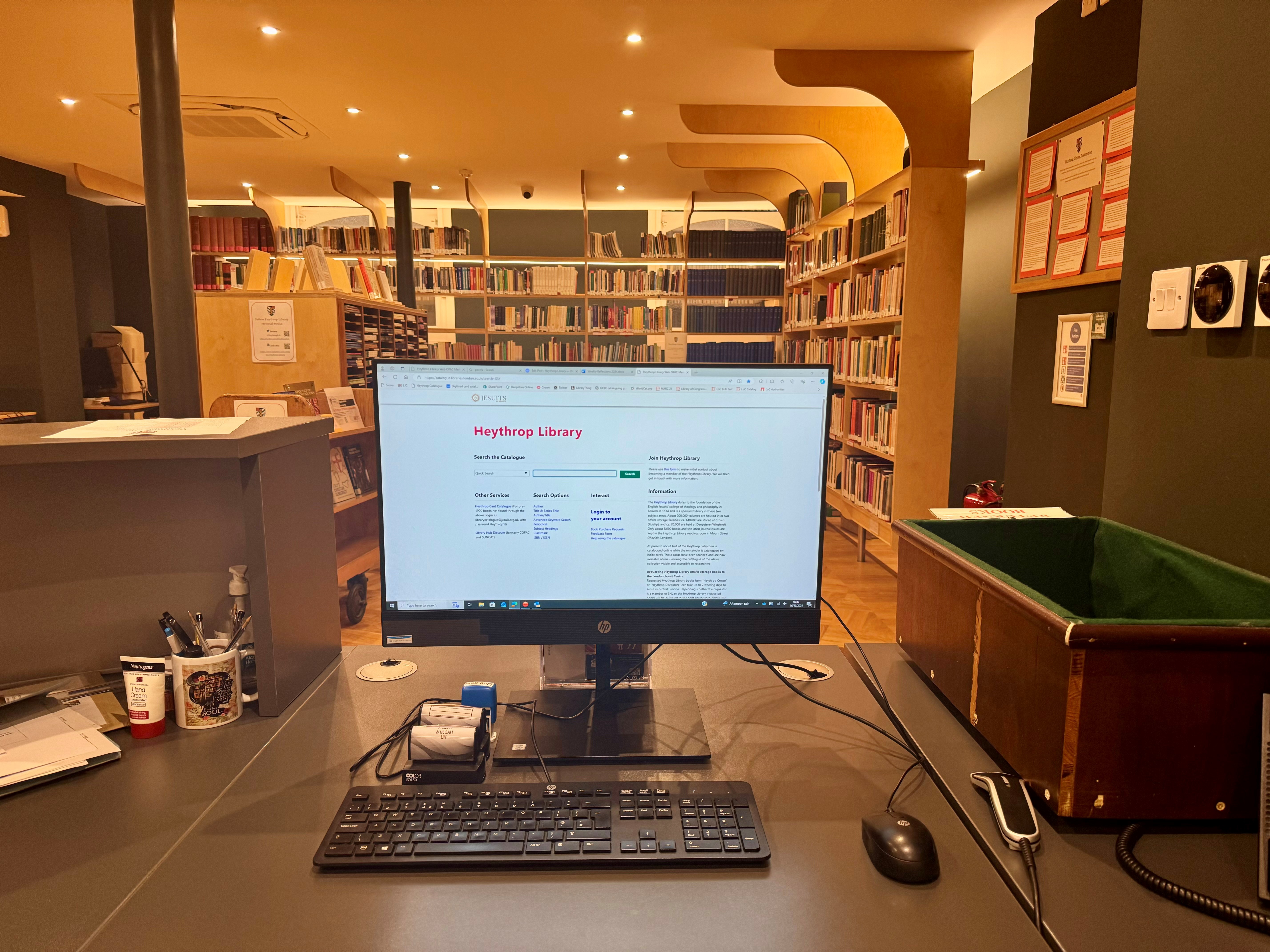 Librarian's desk with computer, book returns box and pen pot.